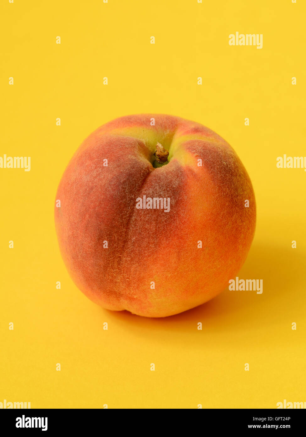 One ripe peach on a yellow background Stock Photo