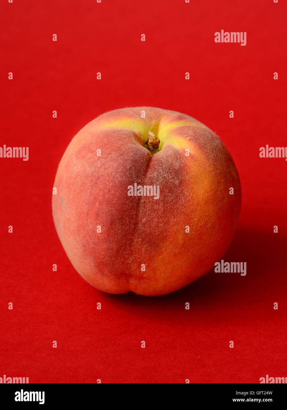 One ripe peach on a red background Stock Photo