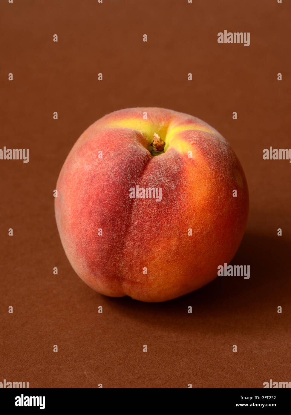 One ripe peach on a brown background Stock Photo