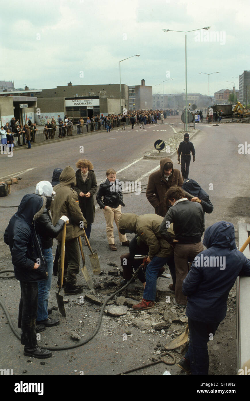 Riots rioting youths digging up the road ( Shankill Road ) to make missiles to throw at the British army.  Belfast Northern Ireland Uk 1980s 1981 HOMER SYKES Stock Photo