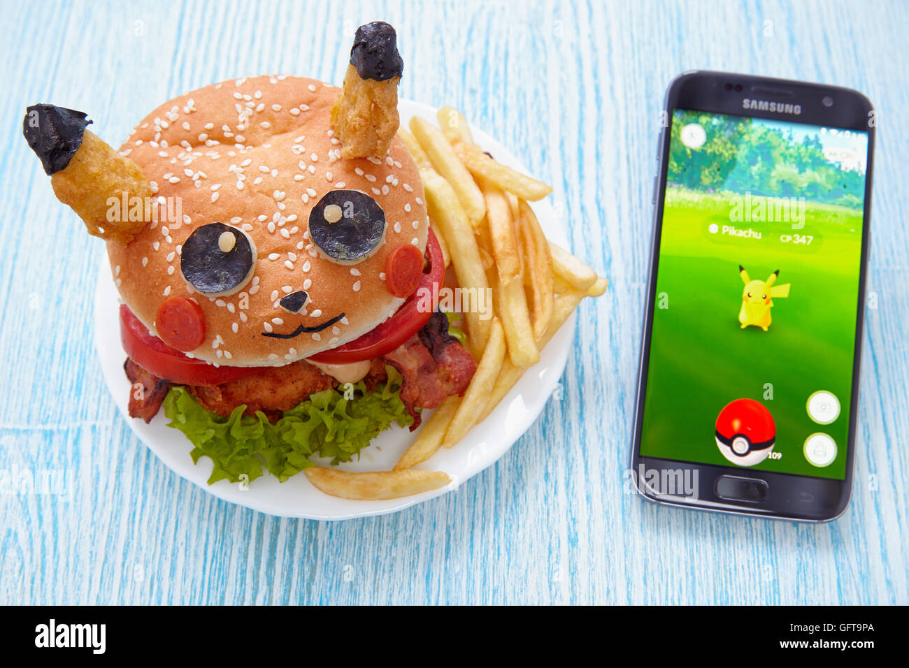 Moscow, Russia - July 29, 2016 Editorial image: Fan Art Pikachu Burger and Smartphone with Pokemon Go application. Selective foc Stock Photo