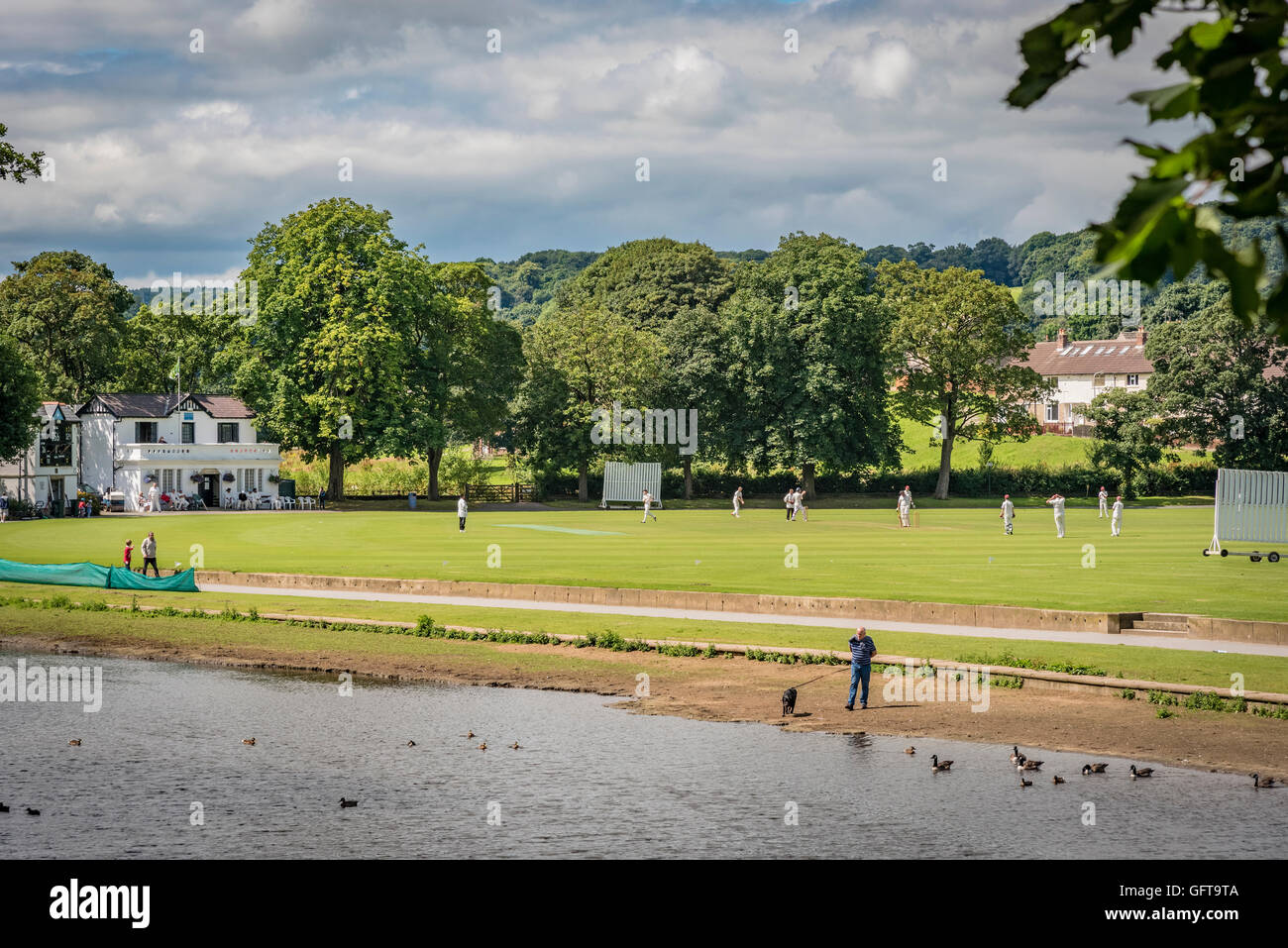 A cricket match being played at Saltaire Cricket Club in Roberts Park by the river Aire in Saltaire West Yorkshire. Stock Photo