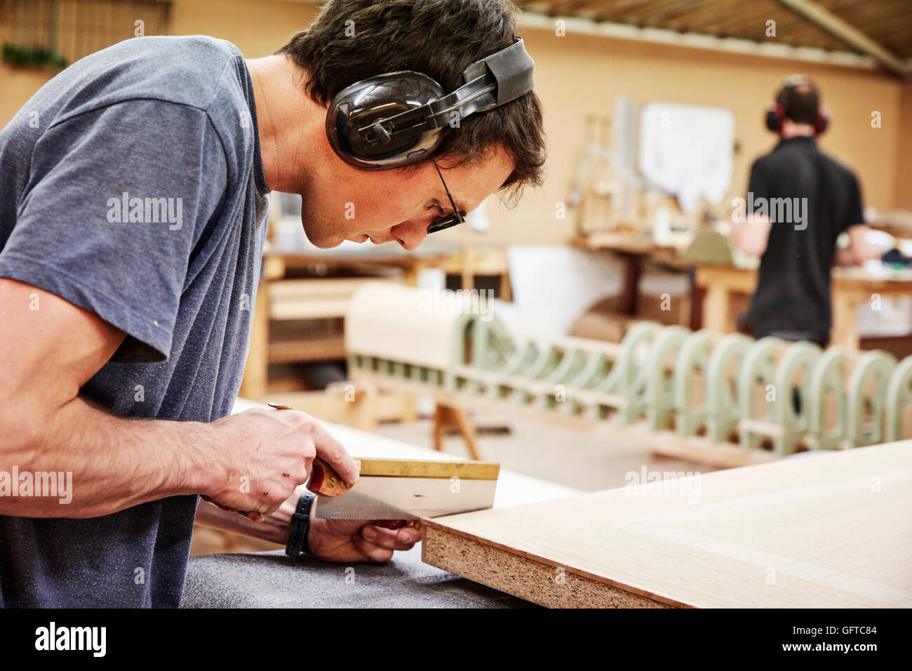 A furniture workshop ,A man using a small handsaw to trim wood Stock Photo