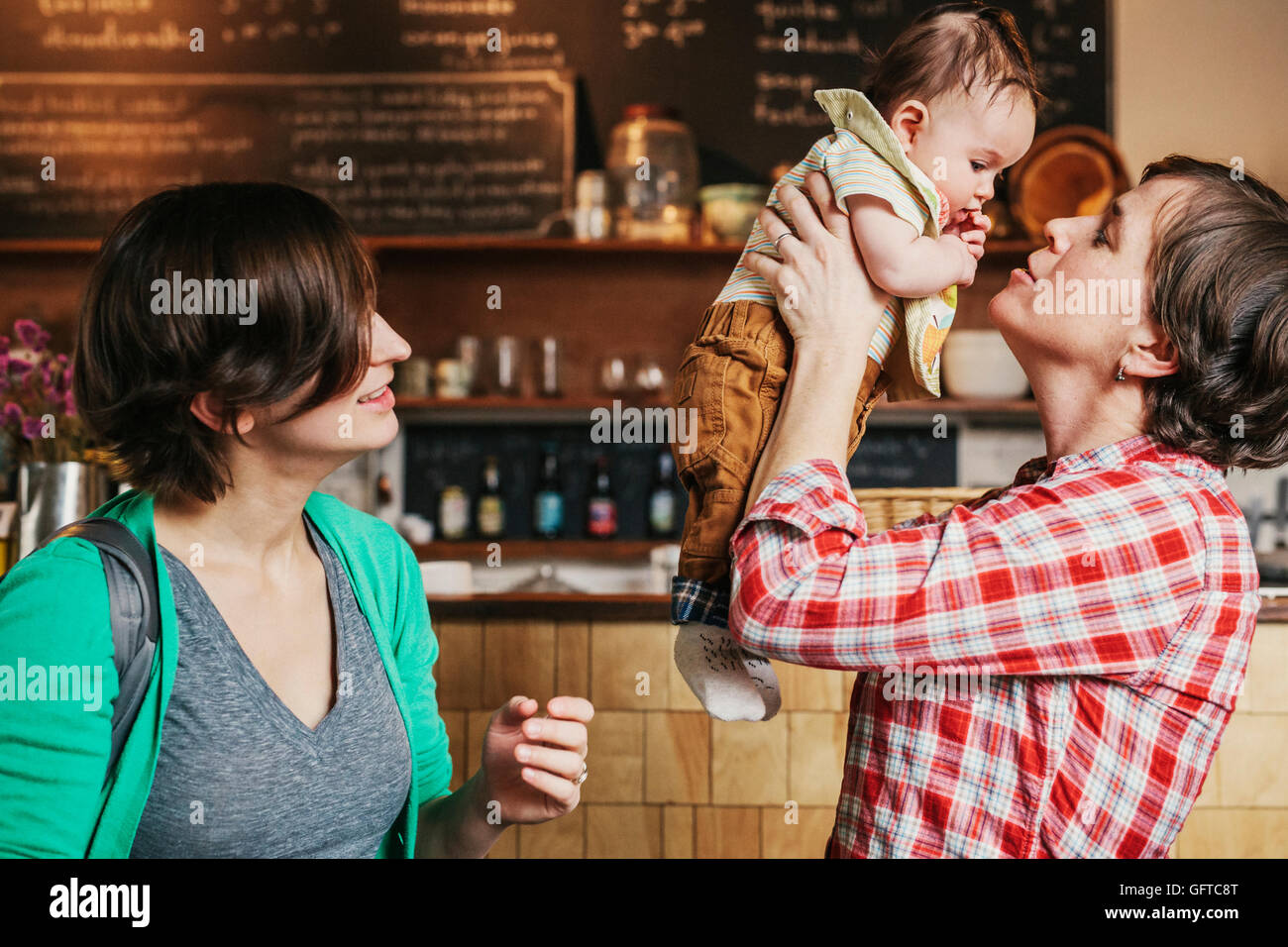 Two women a same sex couple with their 6 month old baby in their coffee shop business owners and parents Stock Photo image