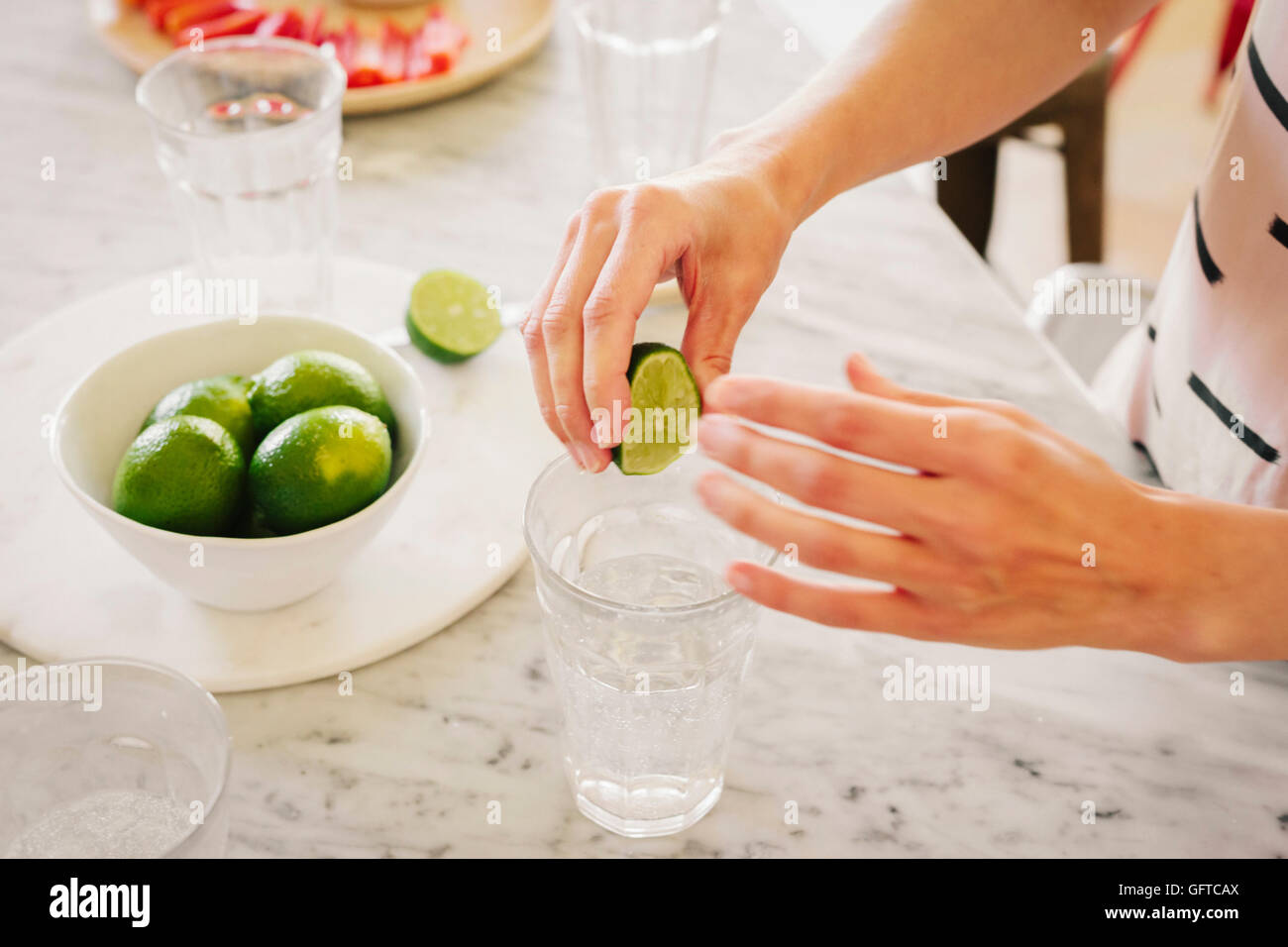 A woman squeezing fresh limes into a glass of water Stock Photo