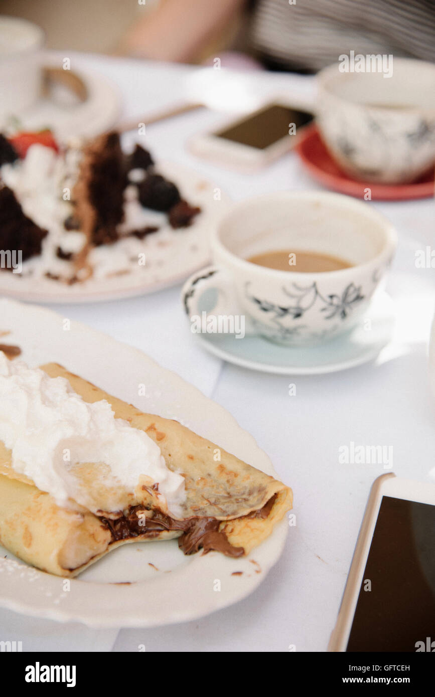 Close up of food and drink on a table a hot drink cake and pancake with cream Stock Photo