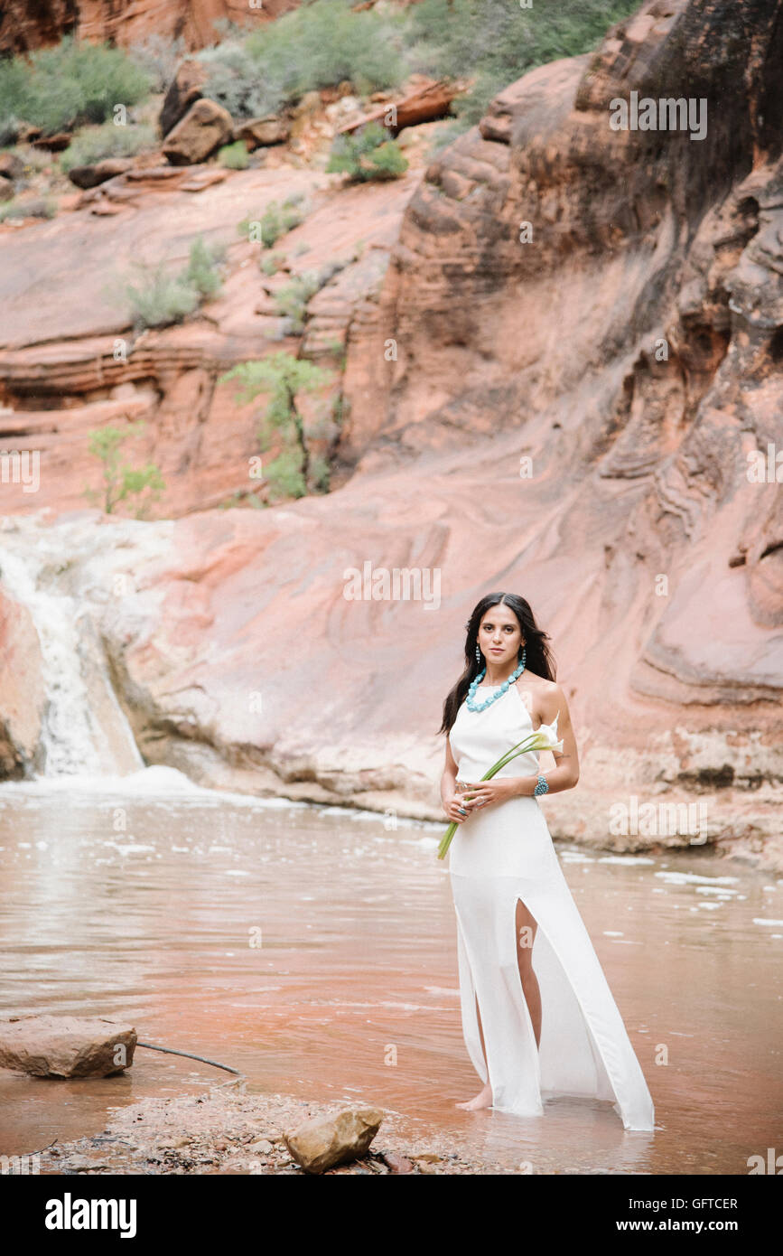 Young woman with long brown hair wearing a long white dress standing by ...