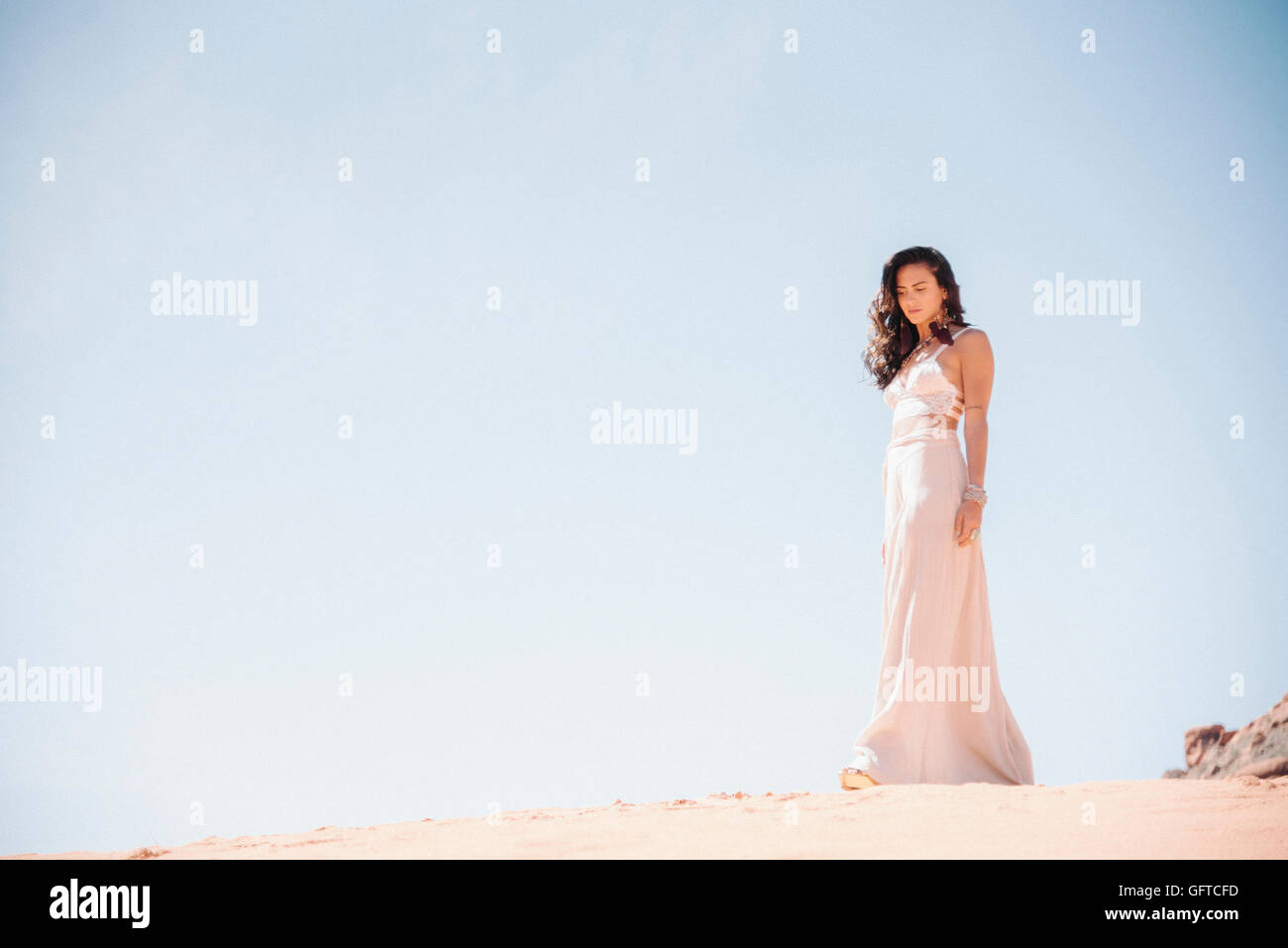 Young woman with long brown hair wearing a long white dress standing in ...