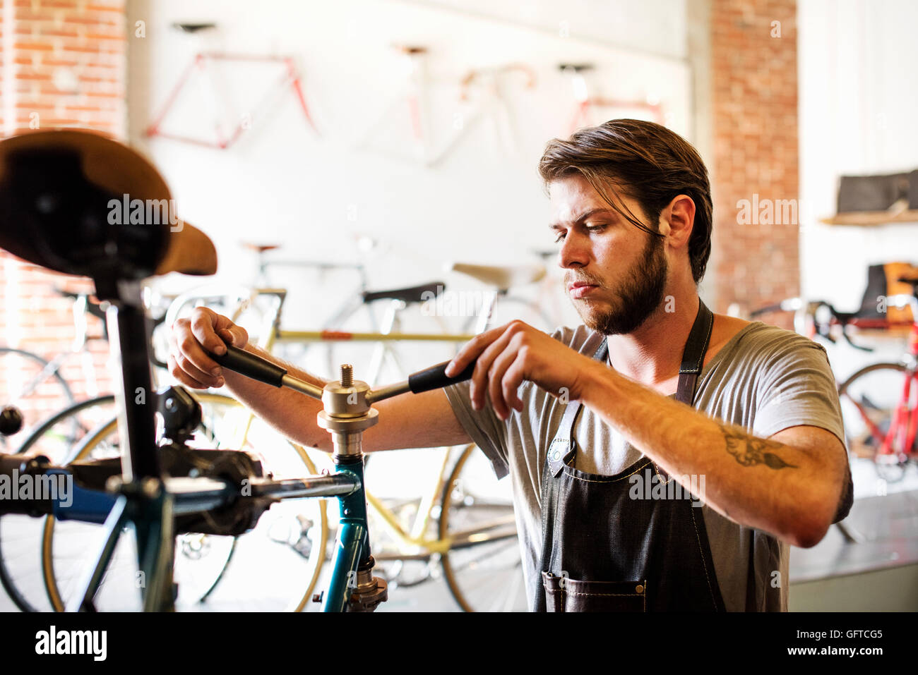 A man working in a bicycle repair shop checking the frame of the bike