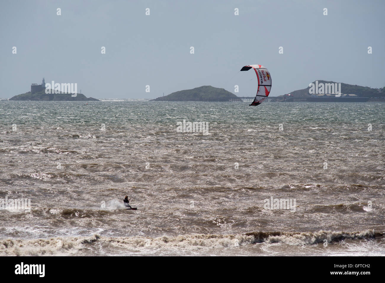 kite surfer harnessing the power of the wind on a windy day in Swansea Bay. The Mumbles are on the Horizon Stock Photo