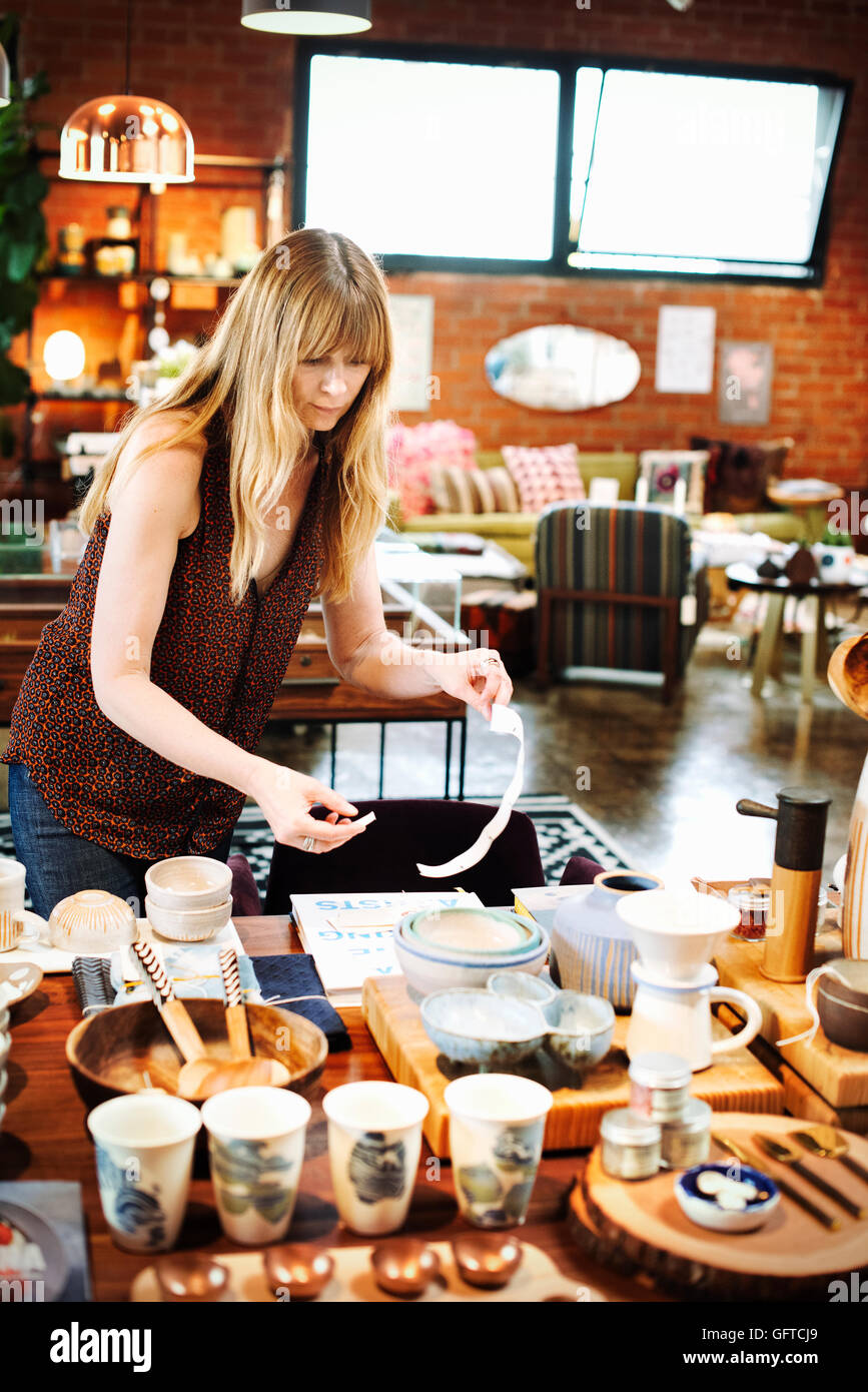Woman standing in a shop arranging merchandise on a table Stock Photo ...