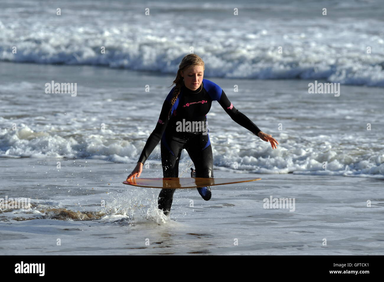 girl skim boarder runs throught the surf preparing to launch her board