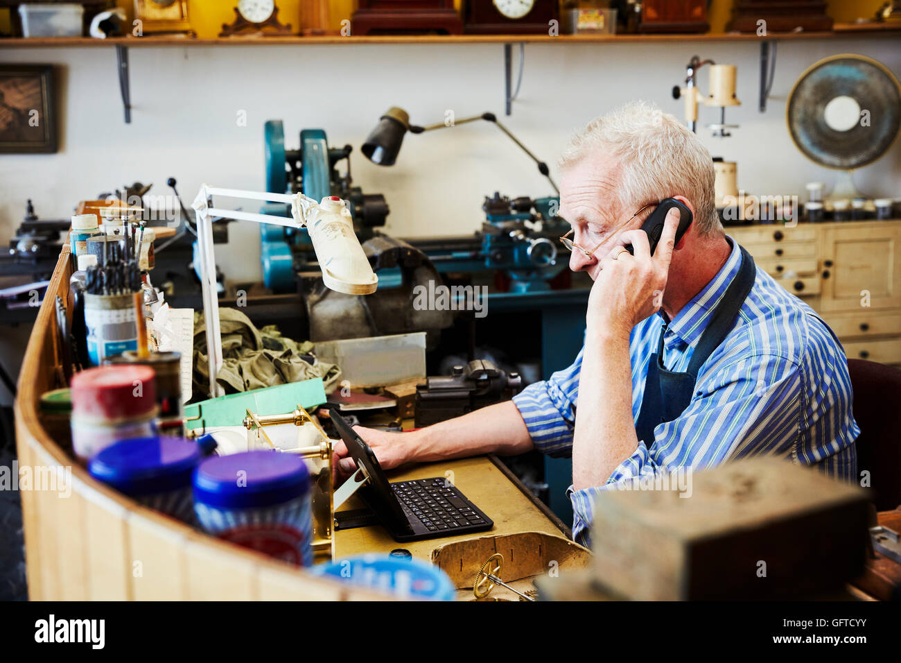 clock maker busy in his on his laptop telephone Stock Photo