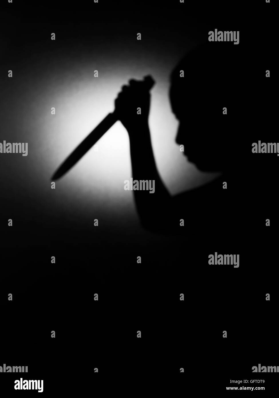 Shadow woman raised a knife to stab . Appears on frosted glass (low key concept) Stock Photo