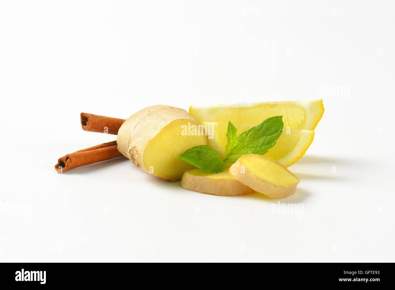 sliced ginger with lemon and cinnamon sticks on white background Stock Photo