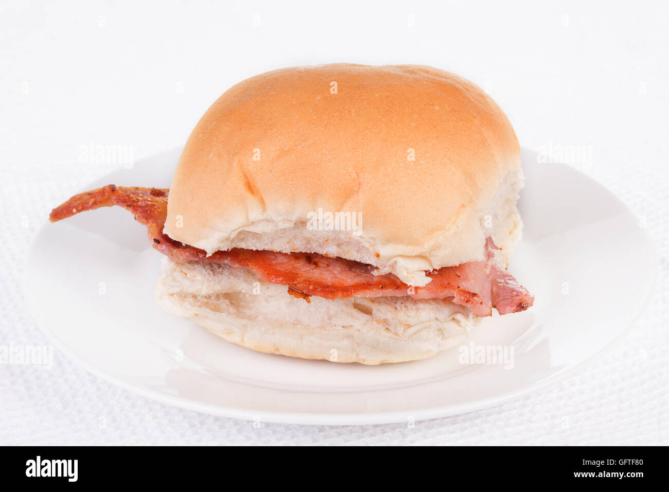 Bacon roll, bap or bun on a white plate. Selective focus Stock Photo