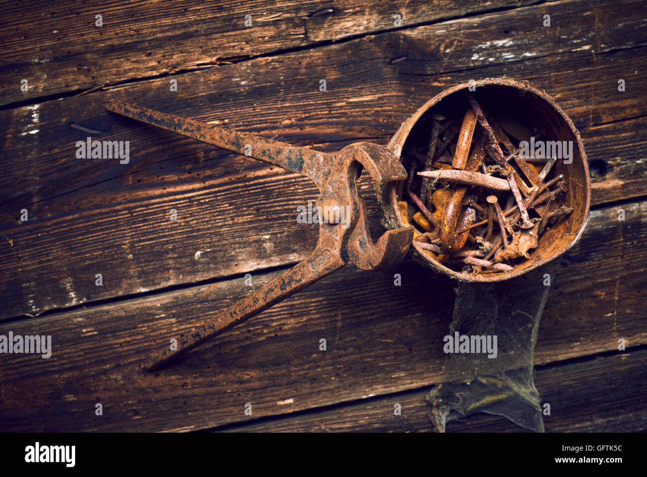 old rusty pinchers with can of nails on wooden boards background Stock Photo