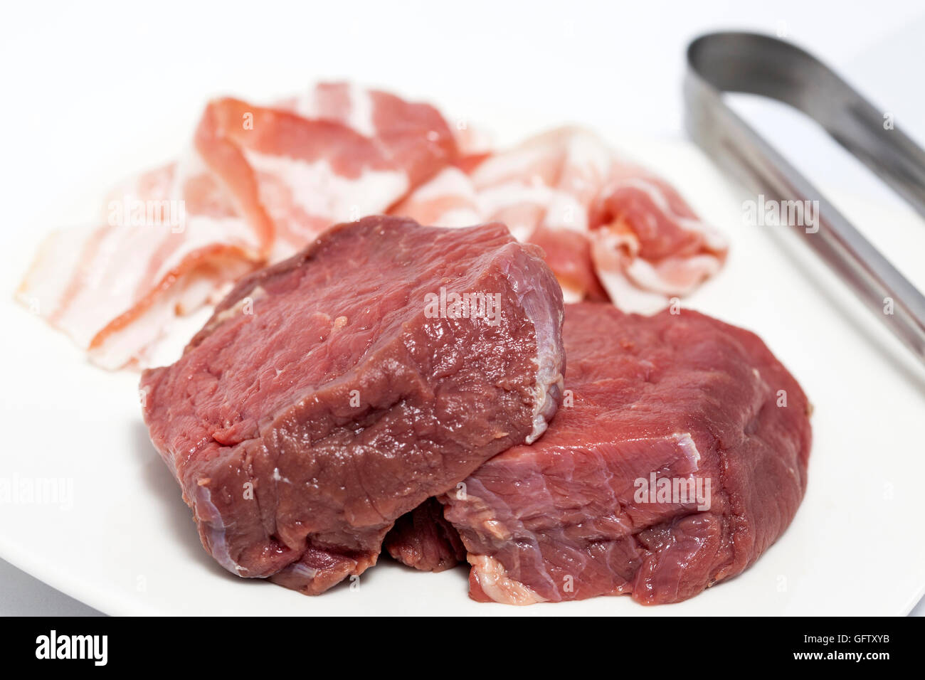 Raw medallions of beef tenderloin and pork bacon Stock Photo