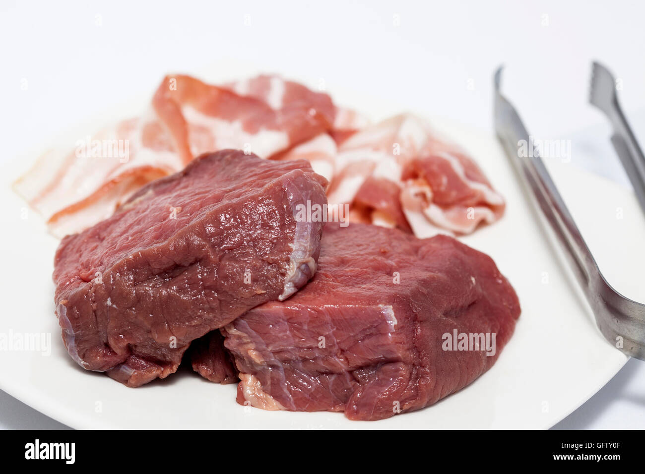 Raw medallions of beef tenderloin and pork bacon Stock Photo