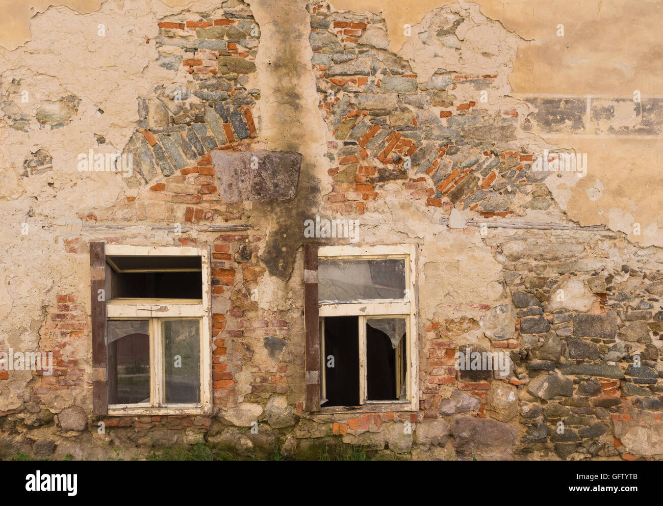 Couple of windows of an abandoned house. Broken glass. Wall of the building  with many details of the colorful bricks and stones Stock Photo - Alamy