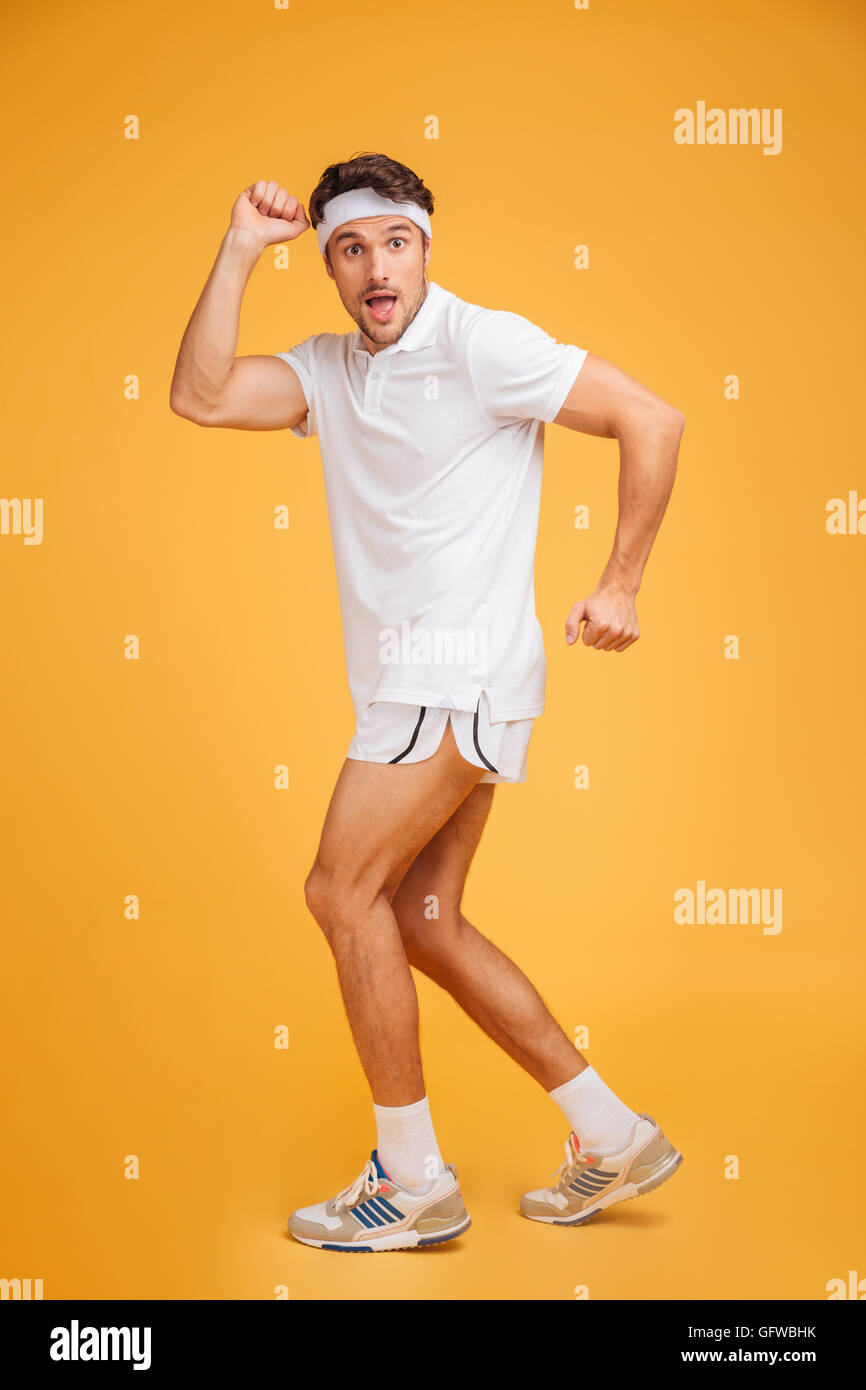 Smiling playful young man athlete standing and posing over yellow background Stock Photo