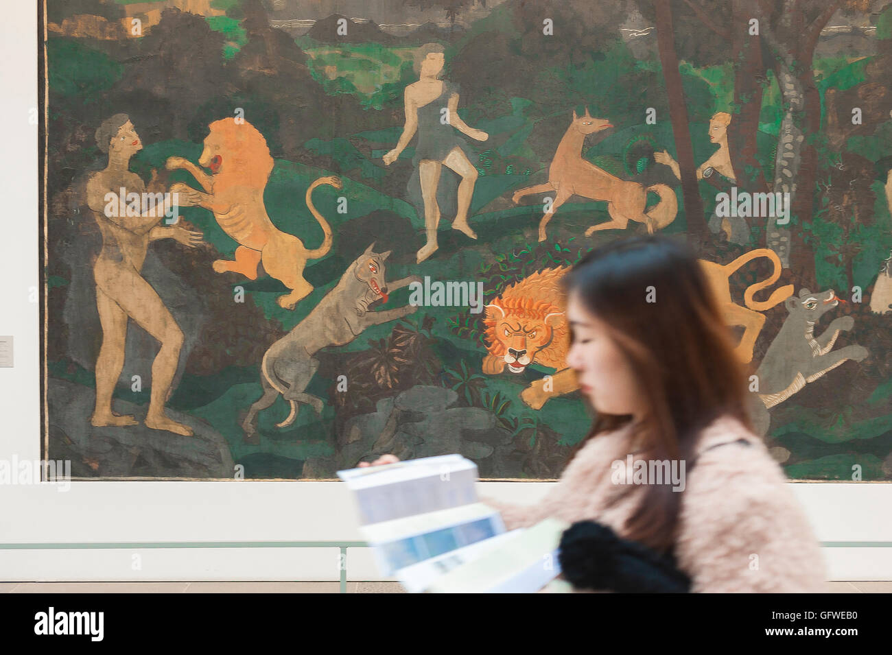 Tourist art, a Japanese tourist walks past a large primitivist painting in the Musee de l'Orangerie in Paris, France. Stock Photo