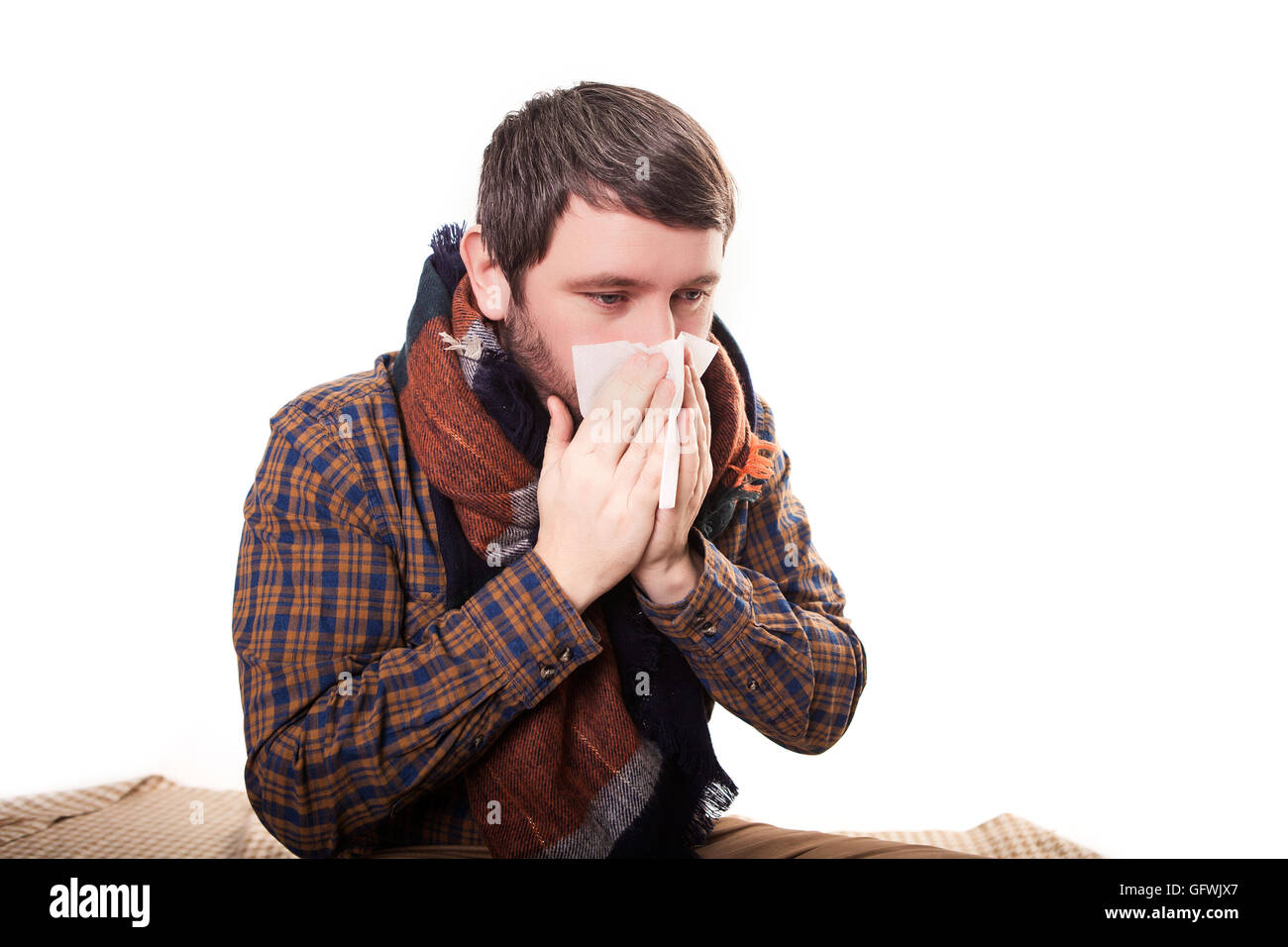 Man with a handkerchief in hand, hands wipes her nose, his eyes PATIENTS AND shine man on a light background Close up looking toward the camera.A guy with a runny nose. Health care for people Stock Photo