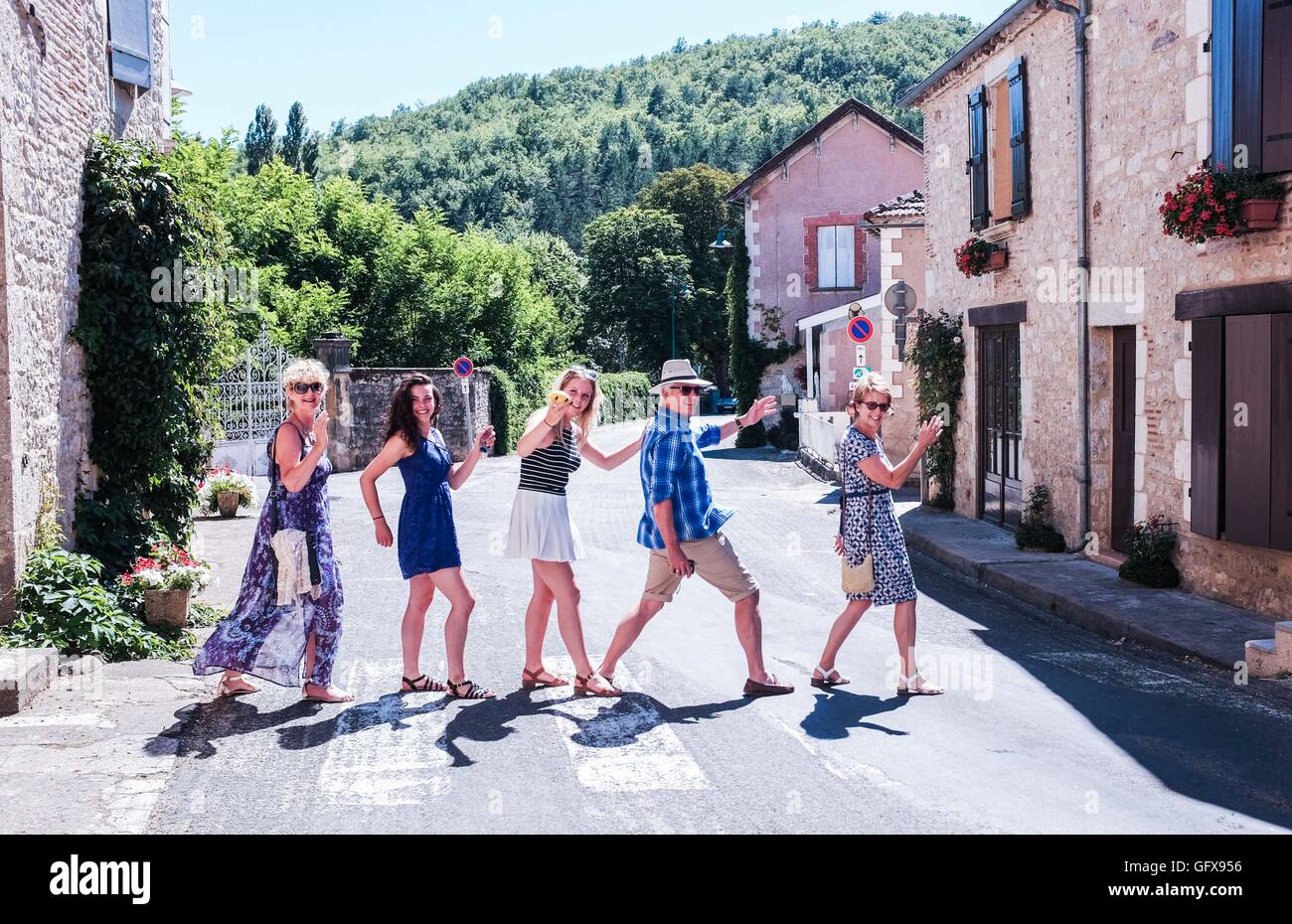 Family and friends on holiday in Lot Region France mimic Beatles Abbey Road album cover at village of Grezels Stock Photo