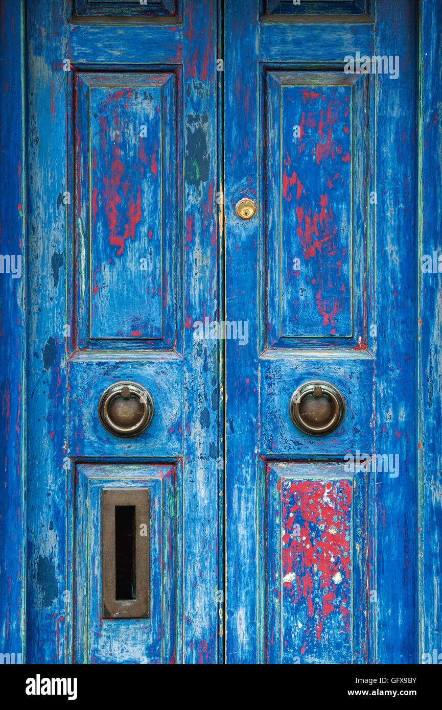 Old rustic blue red painted wooden house doors. Cotswolds, England Stock Photo