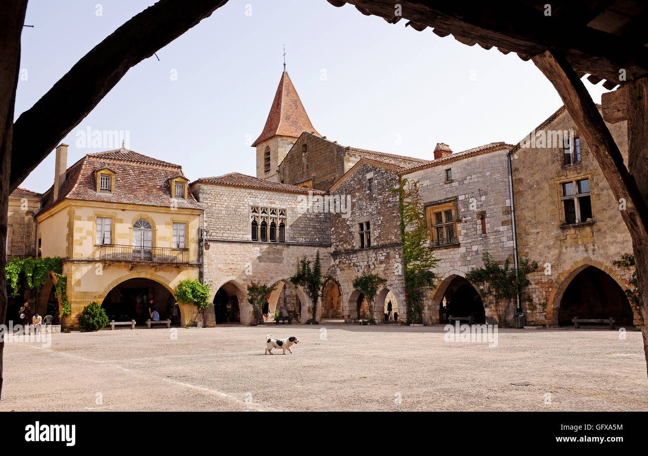 A small dog walks across the famous square in beautiful  bastide of Monpazier in Dordogne region South West France Stock Photo