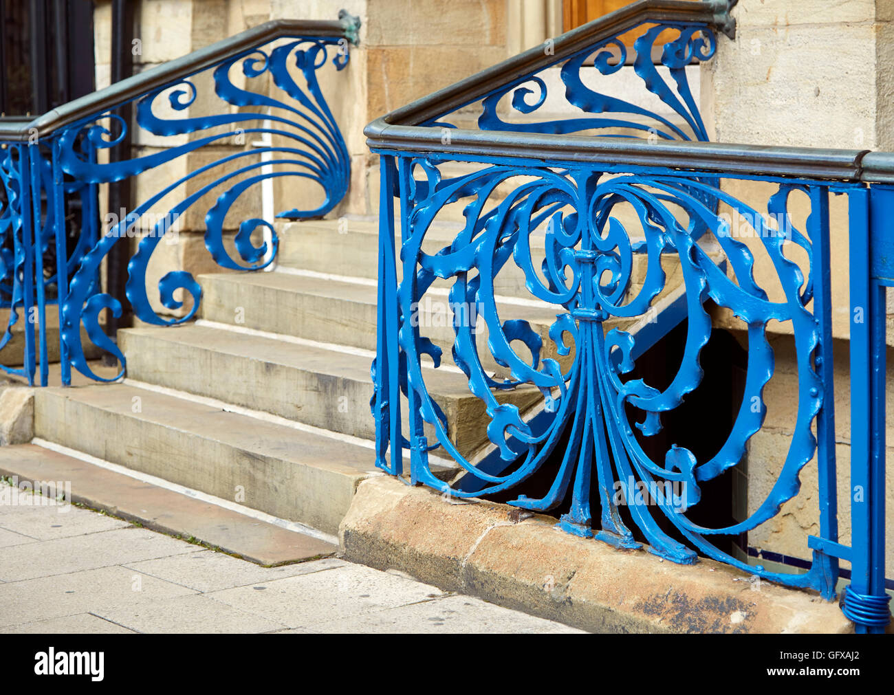 Blue painted art nouveau wrought iron railings swirling ribbons with handrail and steps outside offices in Leeds Stock Photo