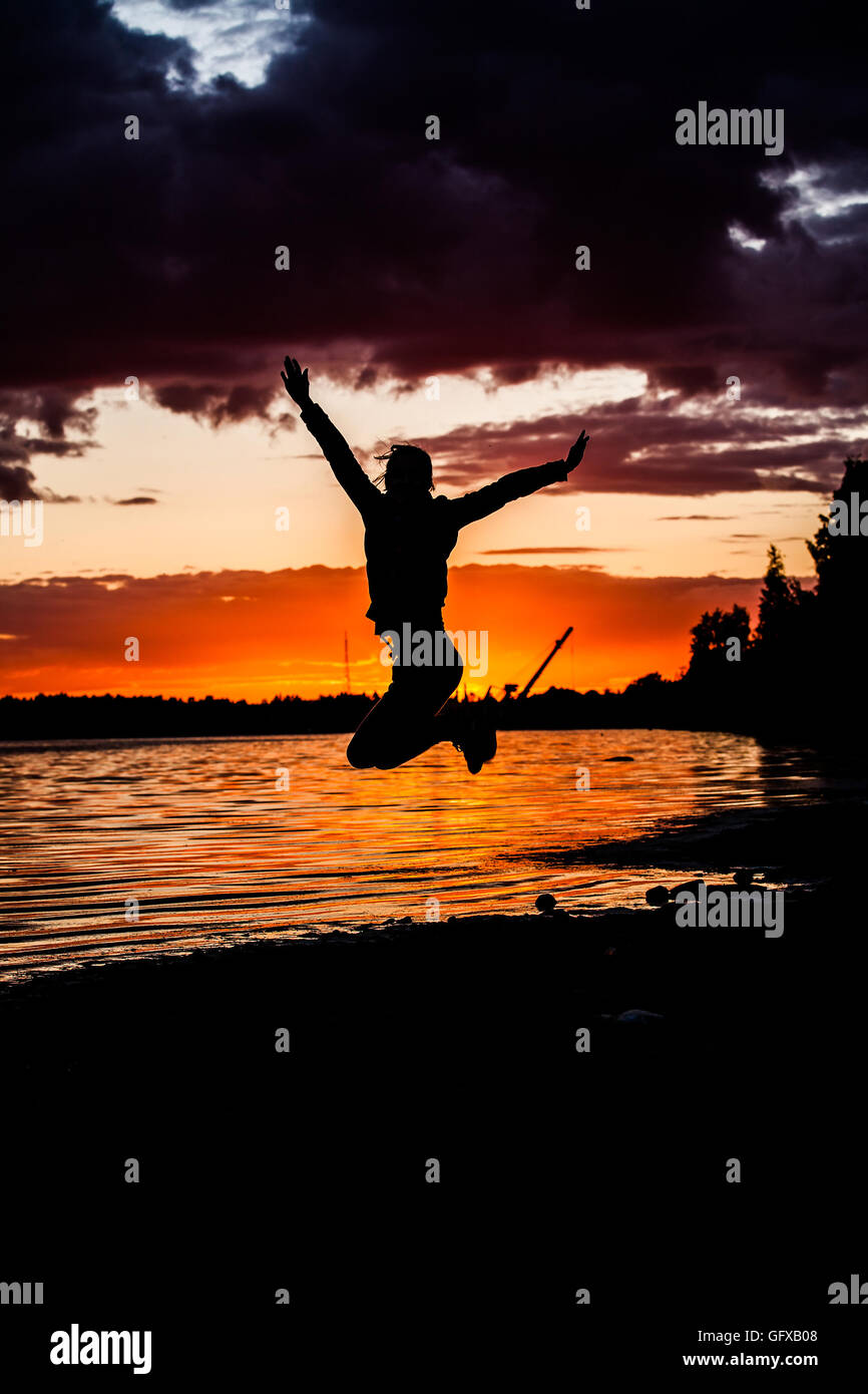Concept of happiness and freedom. Silhouette happy man jumping on a sunset background Stock Photo