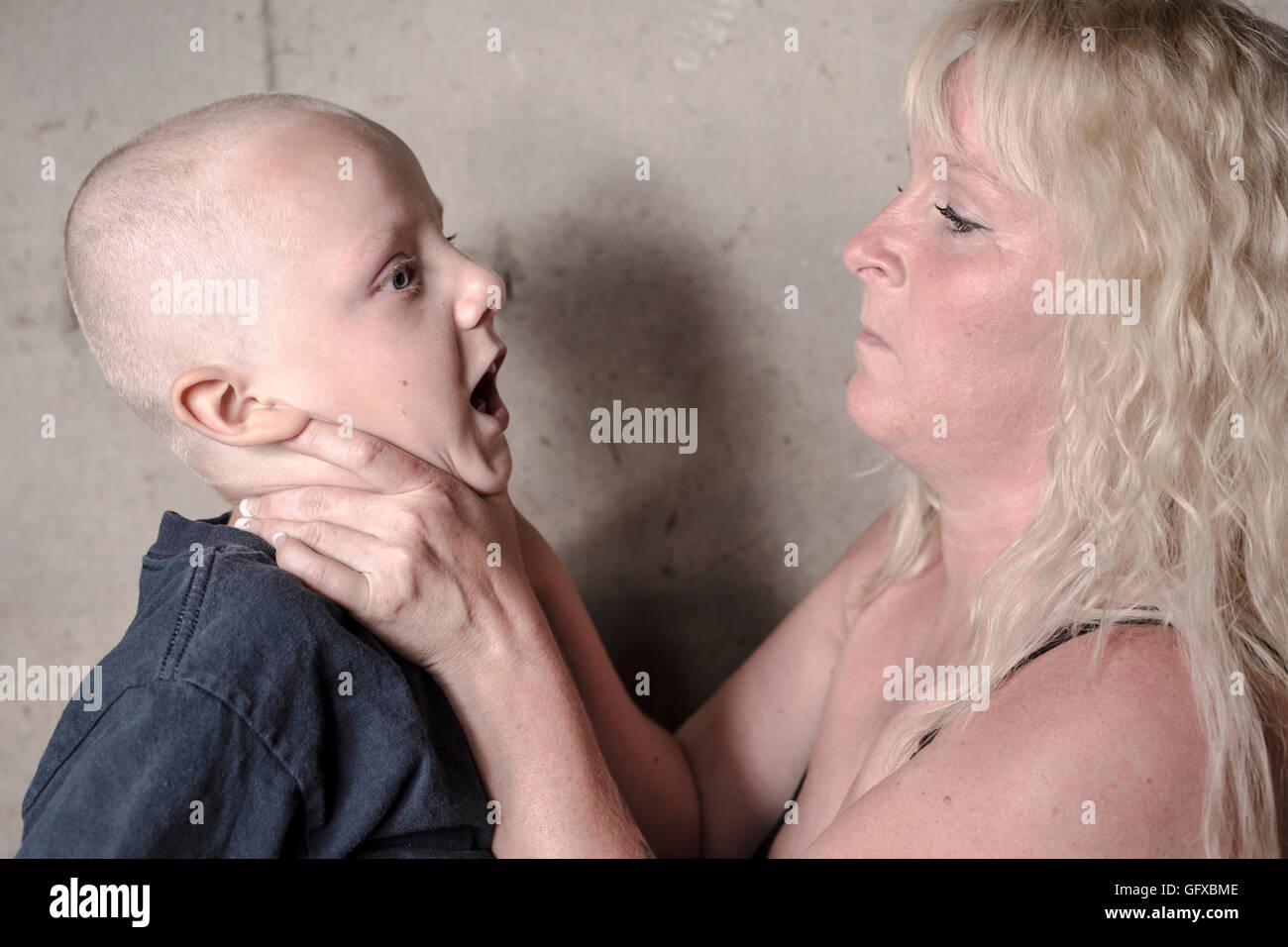 violent mother hit his son in front of a concrete wall Stock Photo