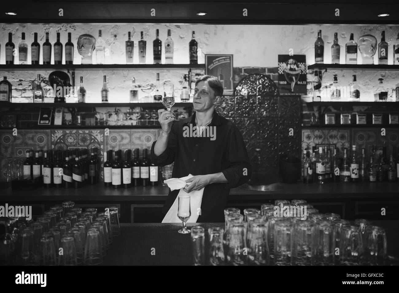 Barman at work in the pub rubs the glass Stock Photo