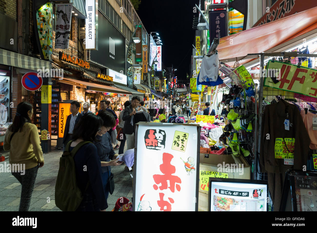 View at night into a busy side street with illuminated advertising and numerous shops close to the Ueno train station in Tokyo Stock Photo