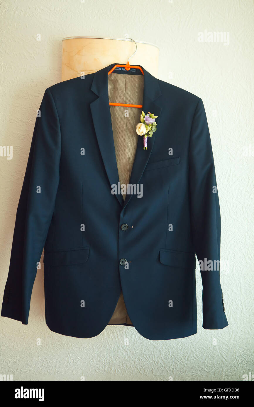 Suit jacket hanging on a hanger with  boutonniere in place Stock Photo