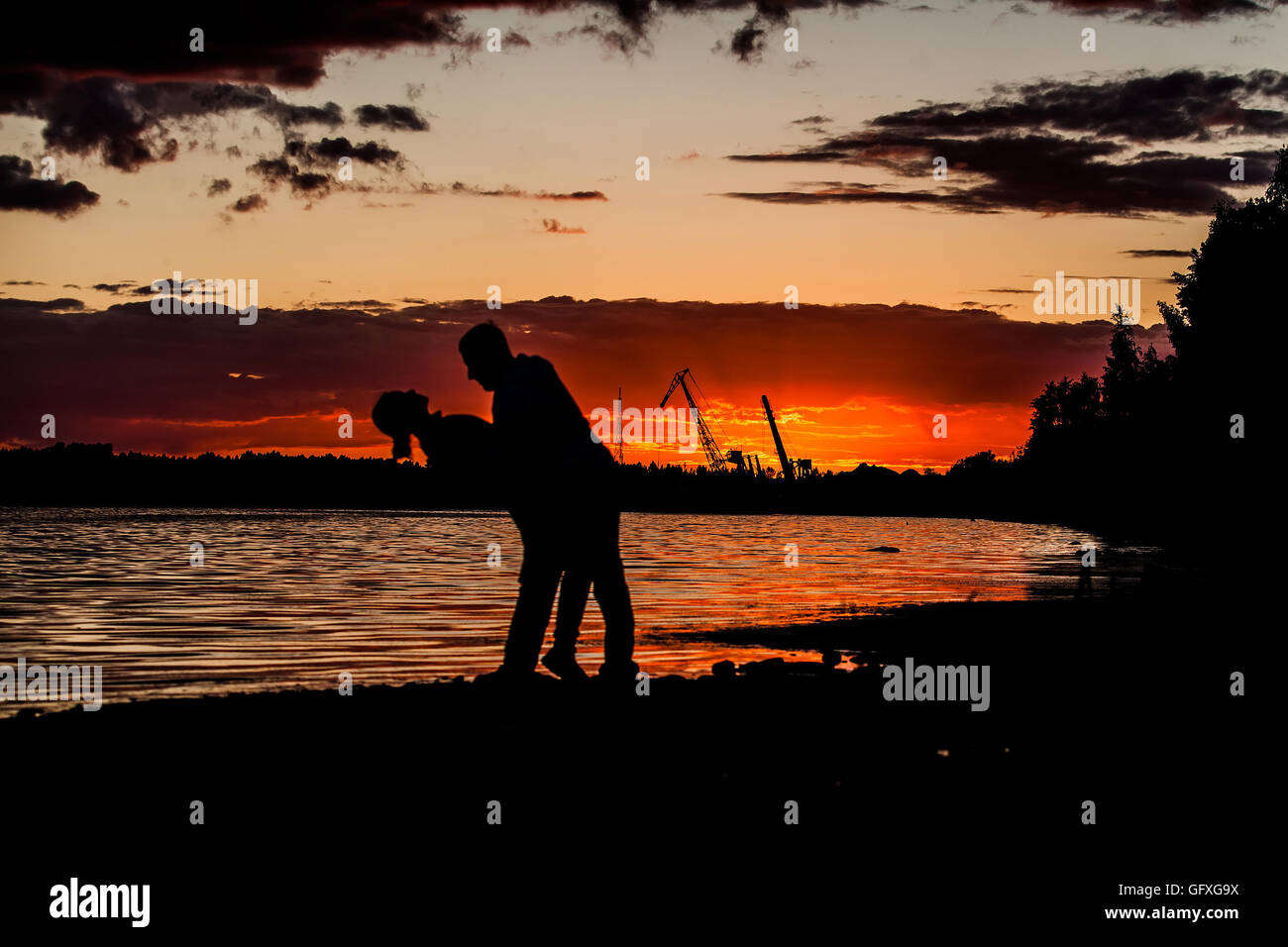 silhouettes of young loving couple on bright sunset sky and sea Stock ...