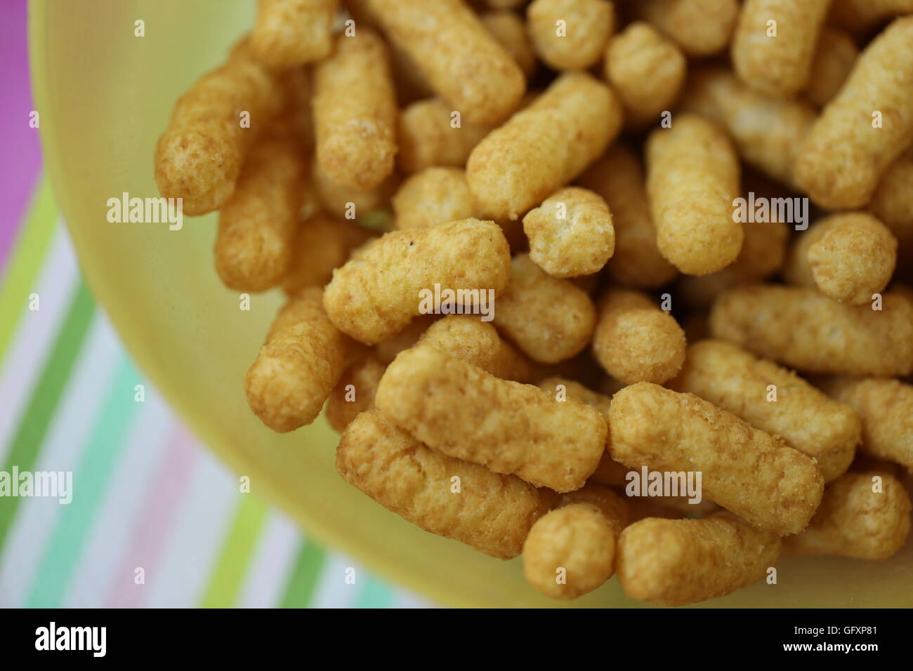Bamba, Israeli Peanut Snack.  Stack of natural salty snack made of peanuts for toddlers and children, in a yellow plastic bowl. Party snack, in the ba Stock Photo