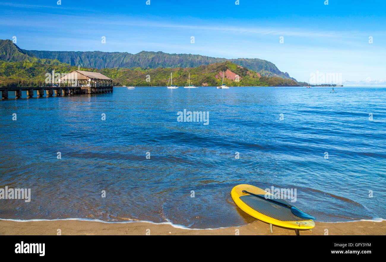 Stand up paddleboard at shoreline of Hanalei Bay near the Hanalei Pier, with Mt. Makana, called Bali Hai, in distance Stock Photo