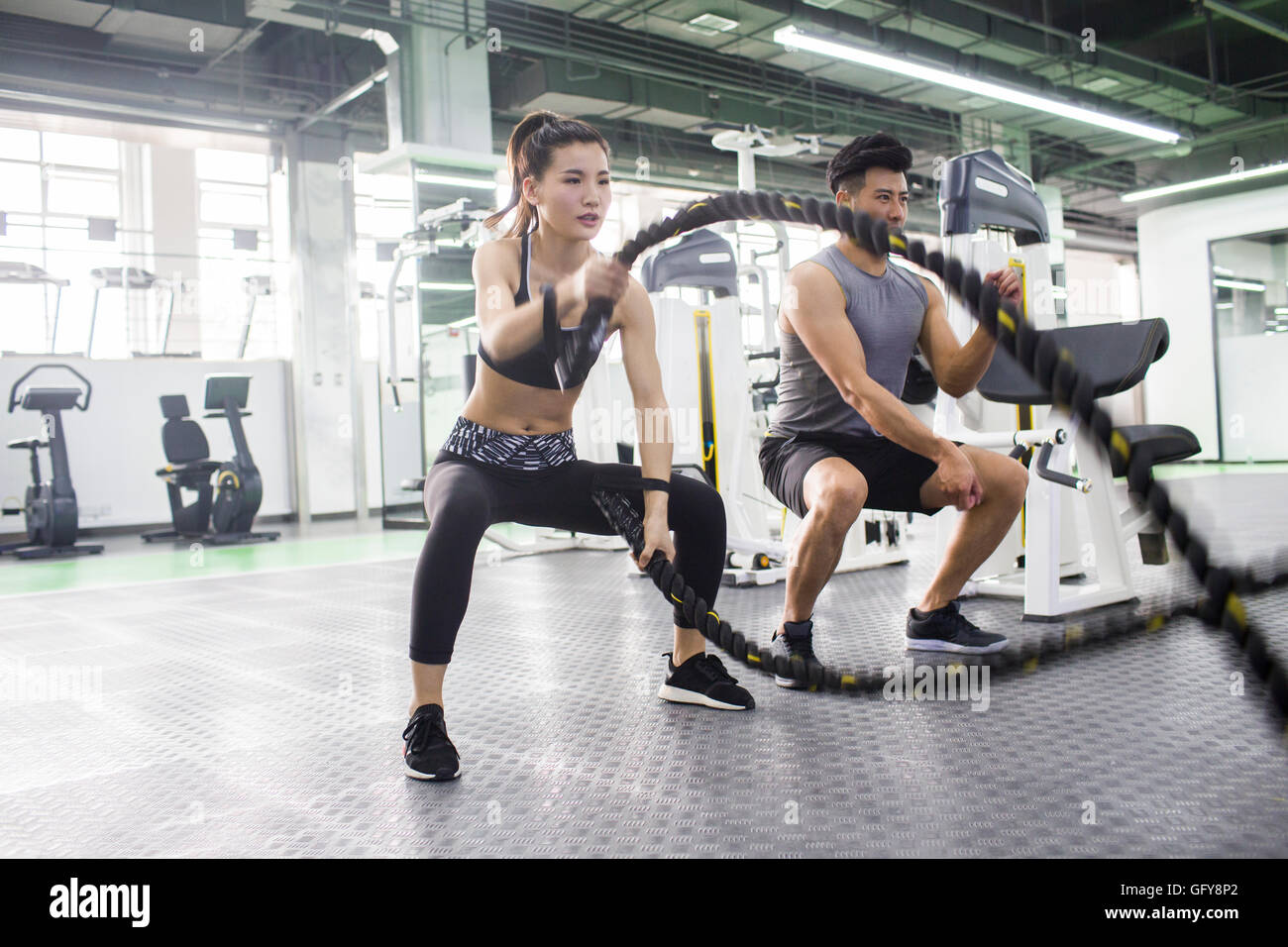 Young Chinese woman working with trainer at gym Stock Photo - Alamy