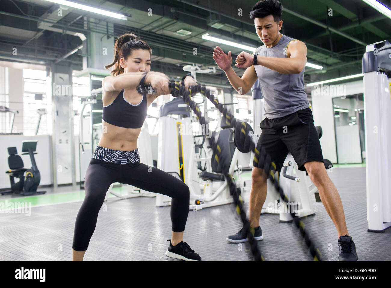 Young Chinese woman working with trainer at gym Stock Photo - Alamy