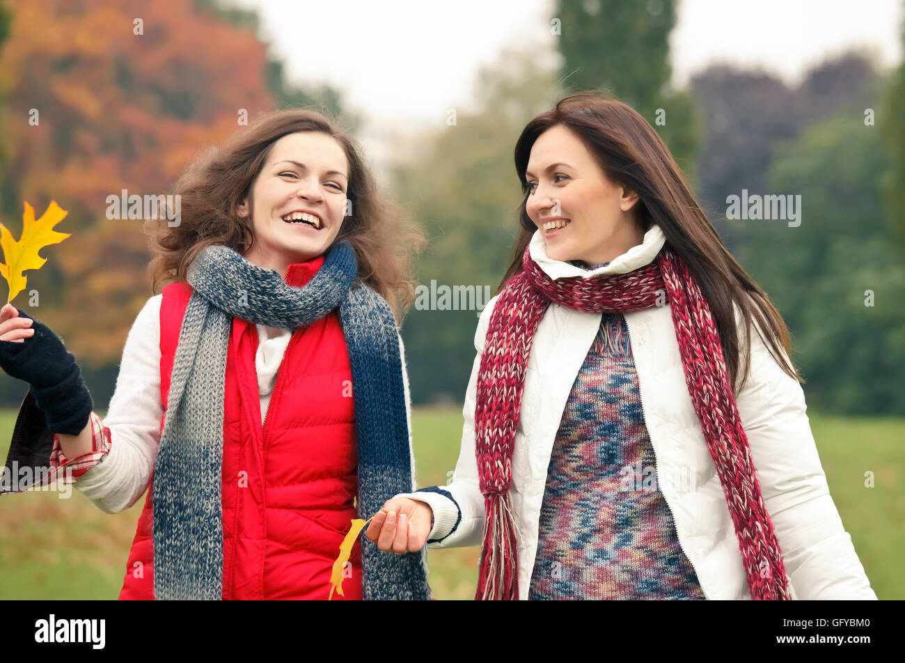 Two young woman walking in autumn park Stock Photo - Alamy
