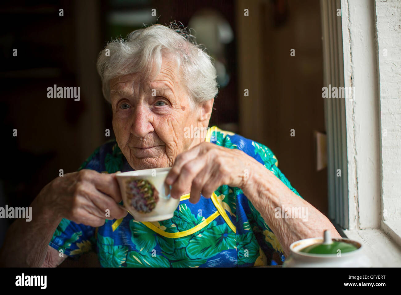 Elderly woman alone drinking tea. Stock Photo