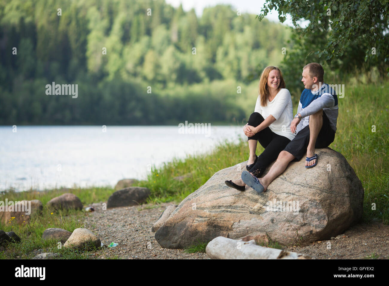 Young couple sitting on a rock by the river. Honeymoon. Stock Photo