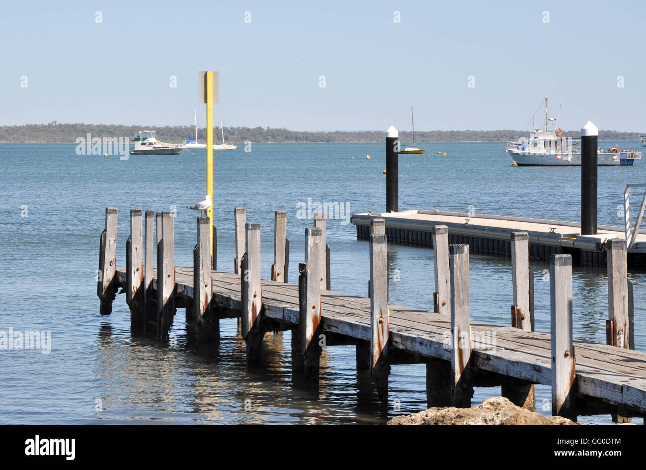 Wooden Jetty And Floating Dock In The Calm River In Mandurah Western Australia With Yachts In The Background Under A Clear Sky Stock Photo Alamy
