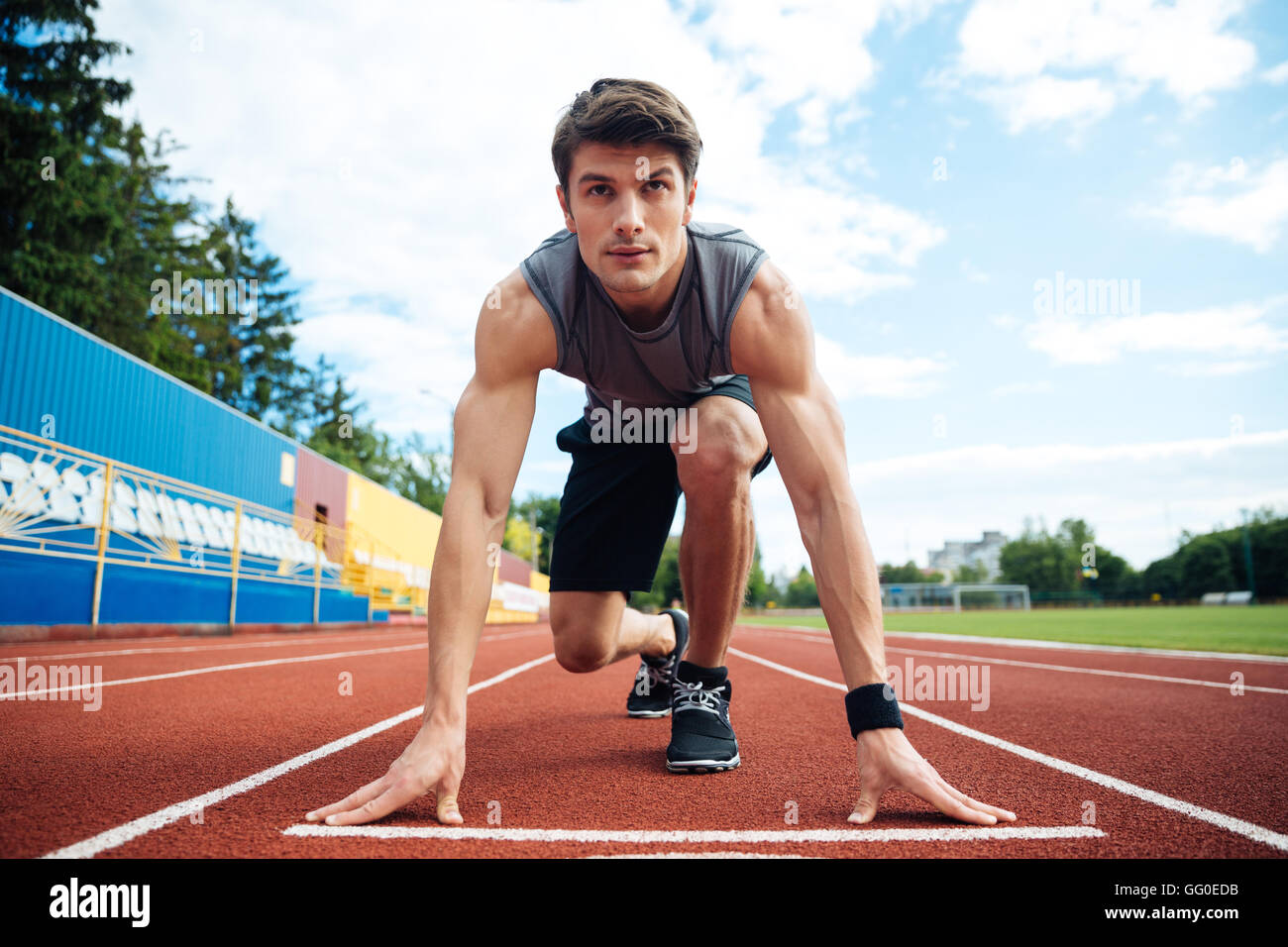 Young handsome man in starting position for running on sports