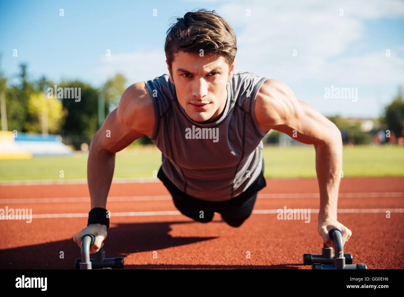 Young male athlete makes push ups on a racetrack at the stadium Stock ...