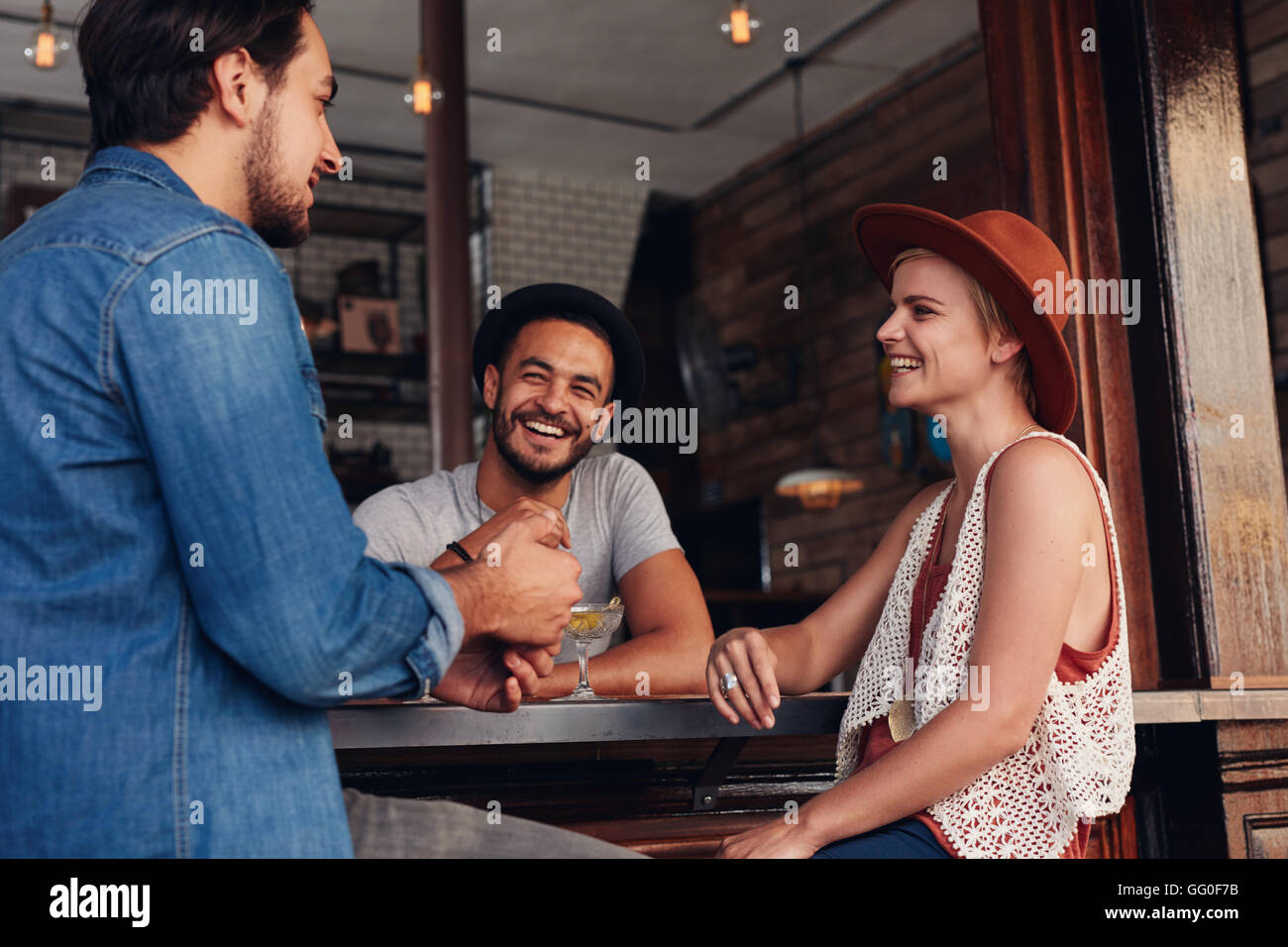 Young men and women sitting together and talking in a coffee shop. Group of young friends hanging out at a cafe. Stock Photo