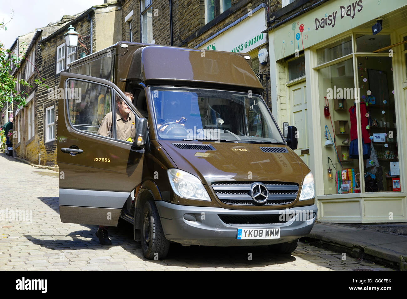Ups van and driver delivering goods on the narrow cobbled streets of Haworth, West Yorkshire, England,UK. Stock Photo