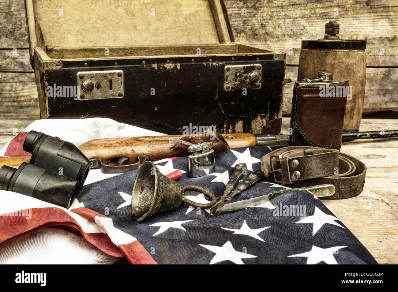 Still life with retro object. Suitcase, bell, rifle, shot, binoculars, USA flag, belt, canteen, flask, lighter, knife, fork. Stock Photo